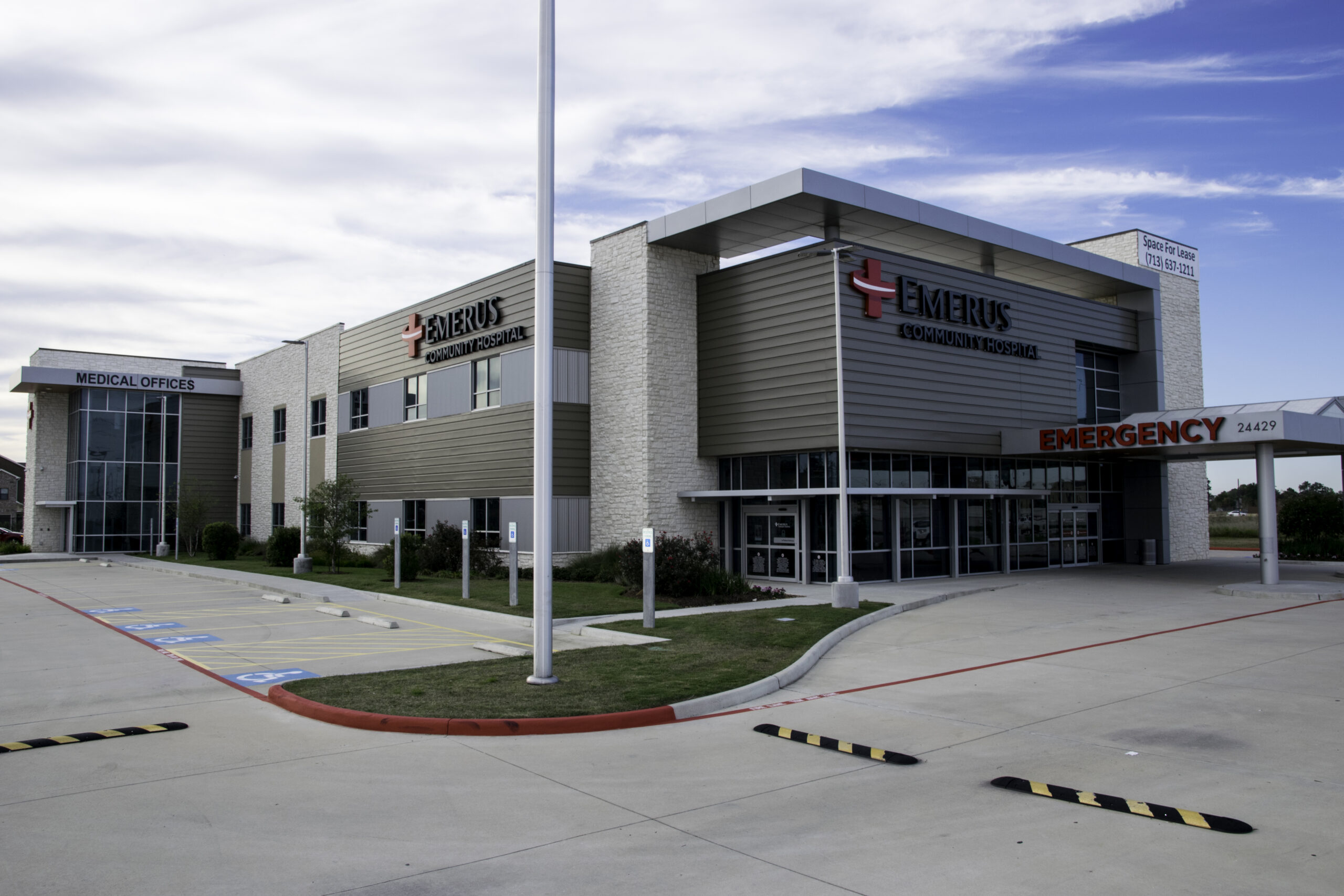 New medical office building with Emerus logo in color on both sides, an emergency entrance on the right side of the building and a parking lot on the left side of the building.