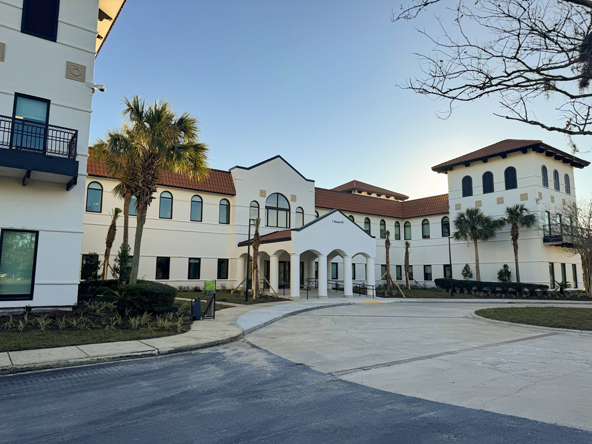 A large white building with a red terra cotta roof with palm trees