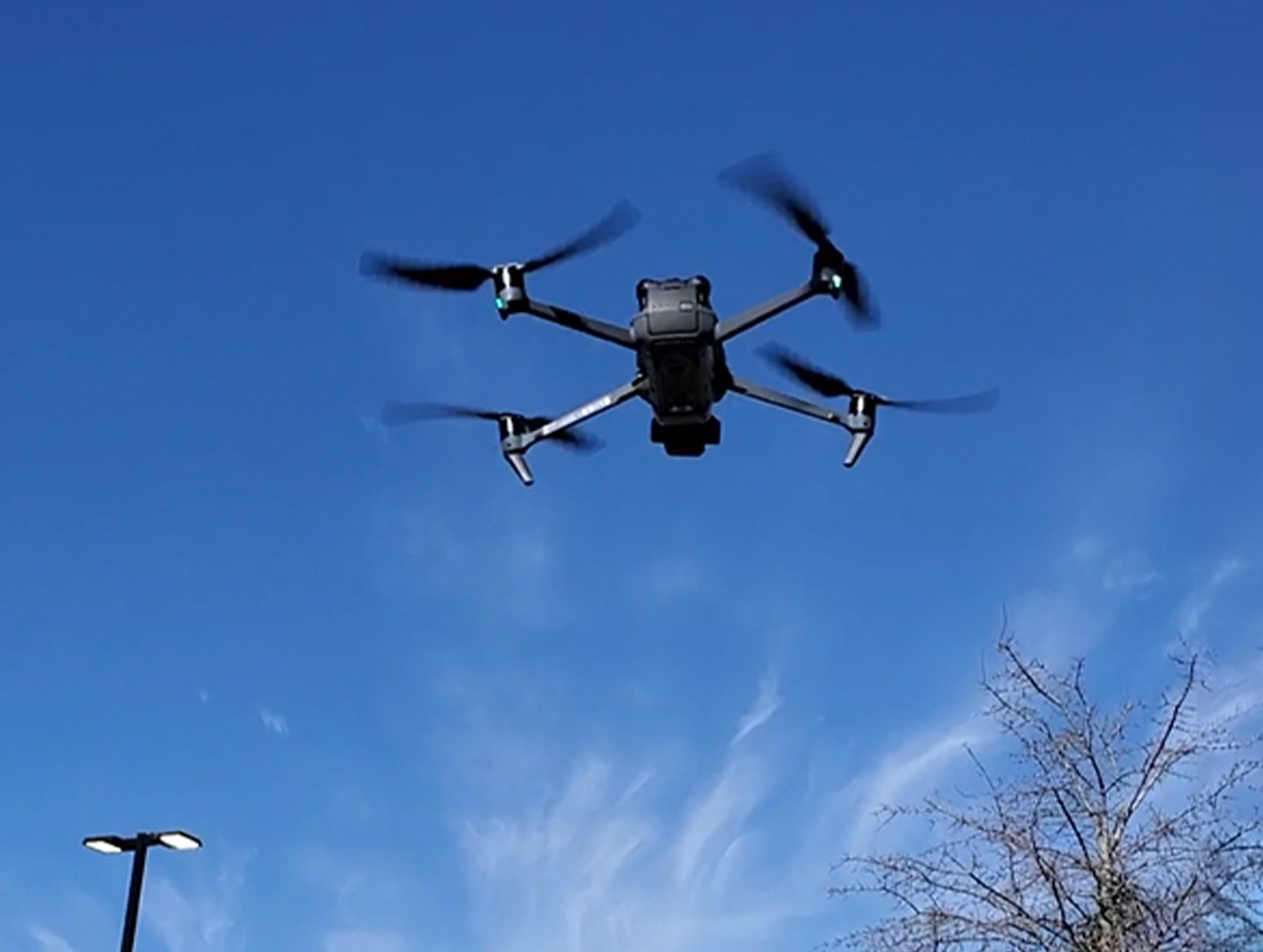 Drone flying against a clear blue sky.